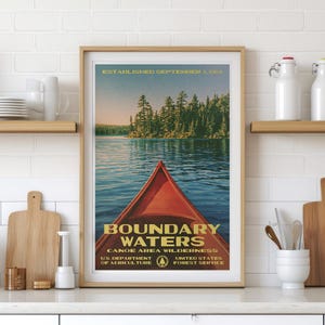 Peut inclure: Une affiche encadr&eacute;e montrant un cano&euml; rouge sur une eau bleue avec une for&ecirc;t en arri&egrave;re-plan. Le texte indique : ESTABLISHED SEPTEMBER 3, 1964, BOUNDARY WATERS CANOE AREA WILDERNESS, U.S. DEPARTMENT OF AGRICULTURE, UNITED STATES FOREST SERVICE.