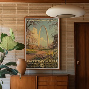 Puede incluir: Un cartel de viaje vintage que presenta el Gateway Arch National Park en St. Louis, Missouri. El cartel est&aacute; en un marco marr&oacute;n y tiene un dise&ntilde;o retro con un cielo azul y &aacute;rboles verdes. El texto en el cartel dice "Established February 22, 1935. Gateway Arch National Park. U.S. Department of the Interior. National Park Service."