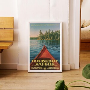 Peut inclure: Une affiche encadr&eacute;e montrant un cano&euml; rouge sur une eau bleue avec une for&ecirc;t en arri&egrave;re-plan. Le texte indique : ESTABLISHED SEPTEMBER 3, 1964, BOUNDARY WATERS CANOE AREA WILDERNESS, U.S. DEPARTMENT OF AGRICULTURE, UNITED STATES FOREST SERVICE.