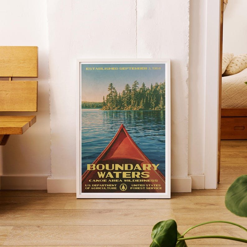 Peut inclure: Une affiche encadr&eacute;e montrant un cano&euml; rouge sur une eau bleue avec une for&ecirc;t en arri&egrave;re-plan. Le texte indique : ESTABLISHED SEPTEMBER 3, 1964, BOUNDARY WATERS CANOE AREA WILDERNESS, U.S. DEPARTMENT OF AGRICULTURE, UNITED STATES FOREST SERVICE.