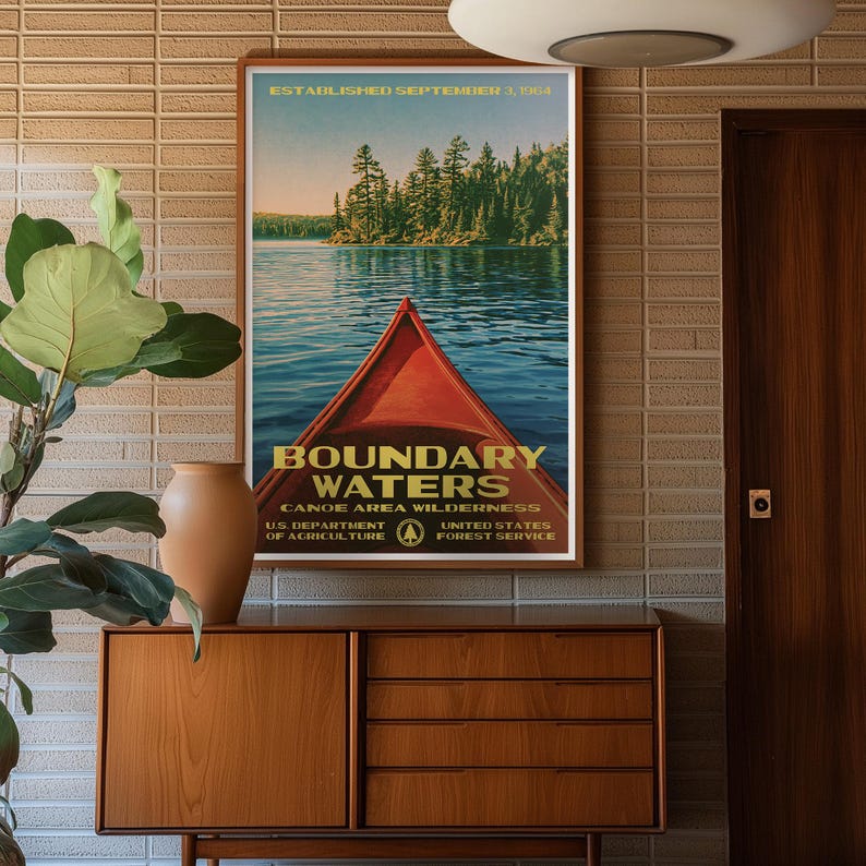 Peut inclure: Une affiche verticale repr&eacute;sentant un cano&euml; rouge sur un lac bleu avec une for&ecirc;t en arri&egrave;re-plan. Le texte indique : ESTABLISHED SEPTEMBER 3, 1964, BOUNDARY WATERS CANOE AREA WILDERNESS, U.S. DEPARTMENT OF AGRICULTURE, UNITED STATES FOREST SERVICE.