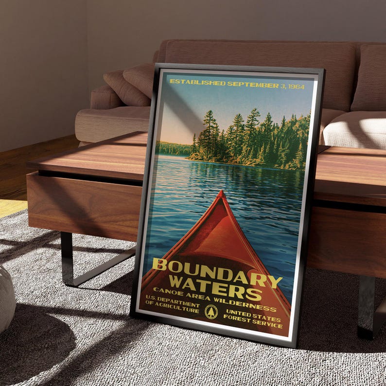 Peut inclure: Une affiche encadr&eacute;e montrant la proue d'un cano&euml; rouge sur une eau bleue, avec une for&ecirc;t en arri&egrave;re-plan et le texte : ESTABLISHED SEPTEMBER 3, 1964, BOUNDARY WATERS CANOE AREA WILDERNESS, U.S. DEPARTMENT OF AGRICULTURE, UNITED STATES FOREST SERVICE.