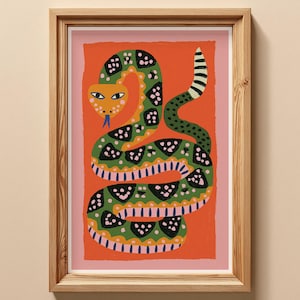 May include: A framed art print featuring a stylized green snake with black and pink patterned markings on a vibrant orange background. The snake has a yellow head, blue tongue, and a black and white striped tail, all encased in a light wood frame.