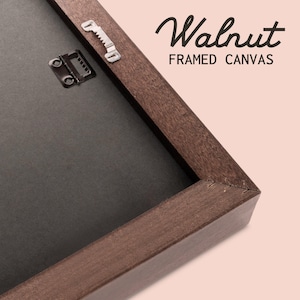 Pu&ograve; includere: Primo piano dell'angolo di una cornice in legno marrone con un retro in tela nero. La cornice &egrave; etichettata "Walnut Framed Canvas".