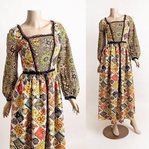 May include: A long, vintage maxi dress with a patchwork design featuring a mix of floral and geometric patterns in shades of orange, yellow, brown, and black. The dress has a square neckline, long sleeves, and a fitted bodice with a black velvet sash.