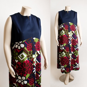 May include: A sleeveless maxi dress with a navy blue bodice and a colorful floral print skirt. The print features geometric shapes, flowers, and leaves in shades of red, green, white, and brown.