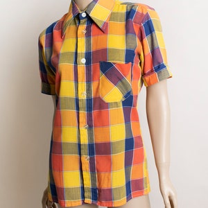 May include: A short-sleeved button-down shirt with a large plaid pattern in shades of yellow, orange, blue, and red.