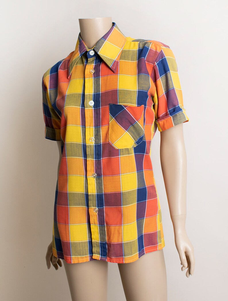 May include: A short-sleeved button-down shirt with a large plaid pattern in shades of yellow, orange, blue, and red.