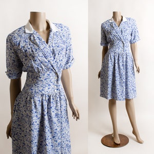 May include: A blue and white floral print dress with a white collar and short sleeves. The dress has a fitted bodice and a full skirt.