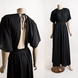 May include: A black maxi dress with a low back and short sleeves. The dress has a fitted bodice and a flowing skirt.