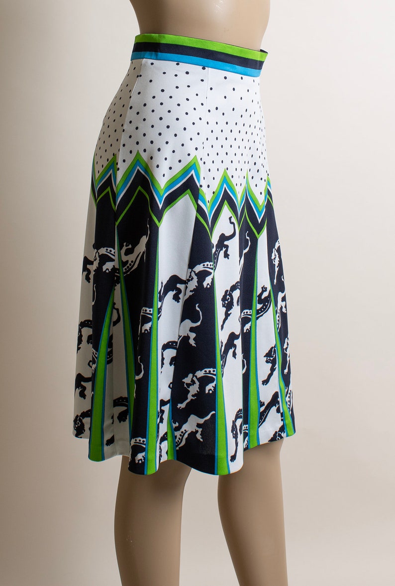 May include: A white skirt with a black and green geometric pattern and white polka dots. The skirt has a blue waistband.