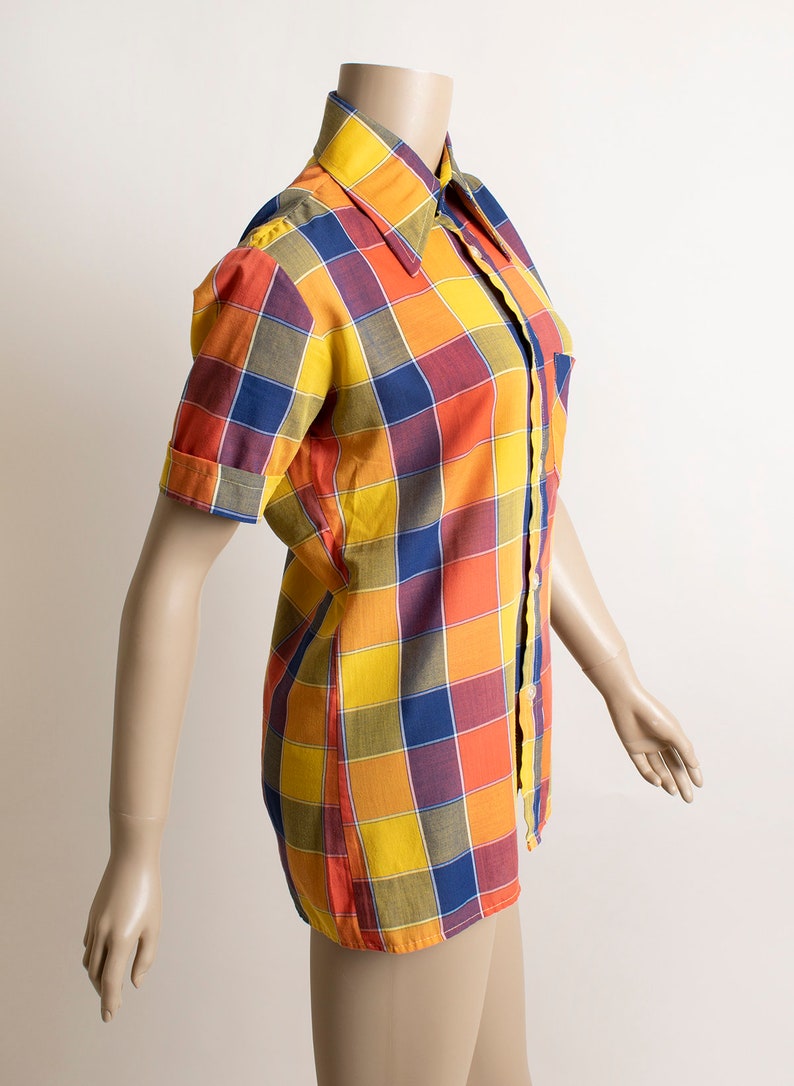 May include: A short-sleeved button-up shirt with a large plaid pattern in shades of yellow, orange, red, blue, and green.