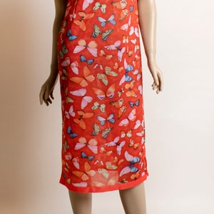 May include: A red dress with a mandarin collar and short sleeves. The dress is covered in a butterfly print with various colors, including pink, blue, and green.