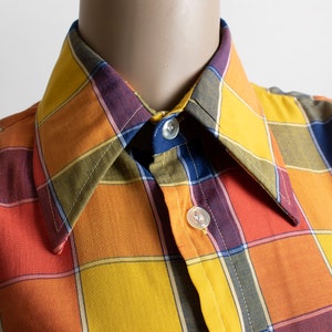 May include: A plaid shirt with a collar, buttons, and a checkered pattern in shades of orange, yellow, red, blue, and green.