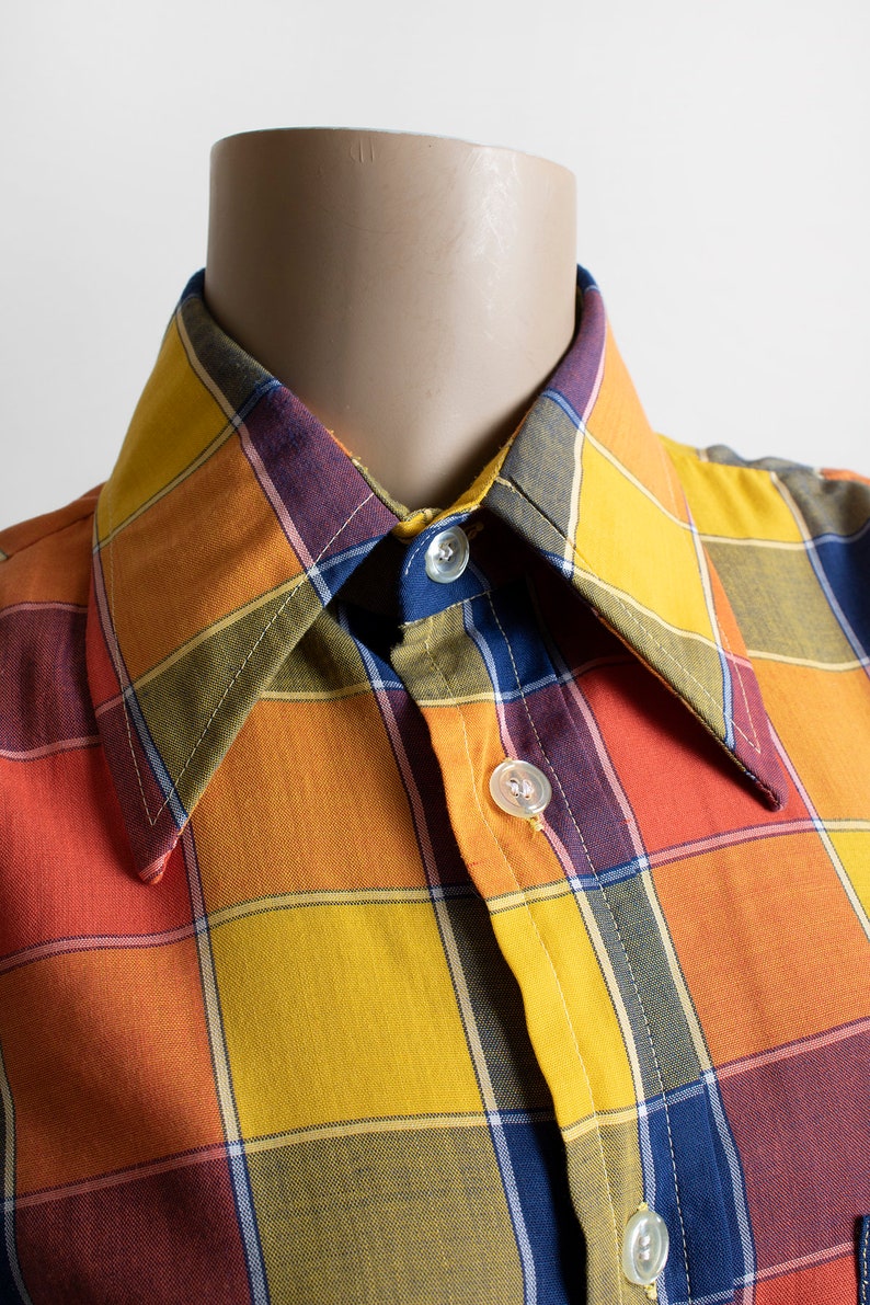May include: A plaid shirt with a collar, buttons, and a checkered pattern in shades of orange, yellow, red, blue, and green.
