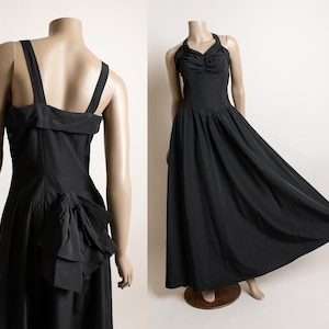 May include: A black sleeveless gown with a fitted bodice and a full skirt. The gown has a bow detail at the back.