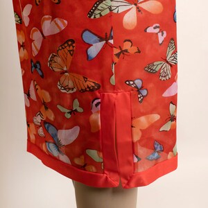 May include: A red sheer dress with a butterfly print. The dress has a side slit and a red satin trim.