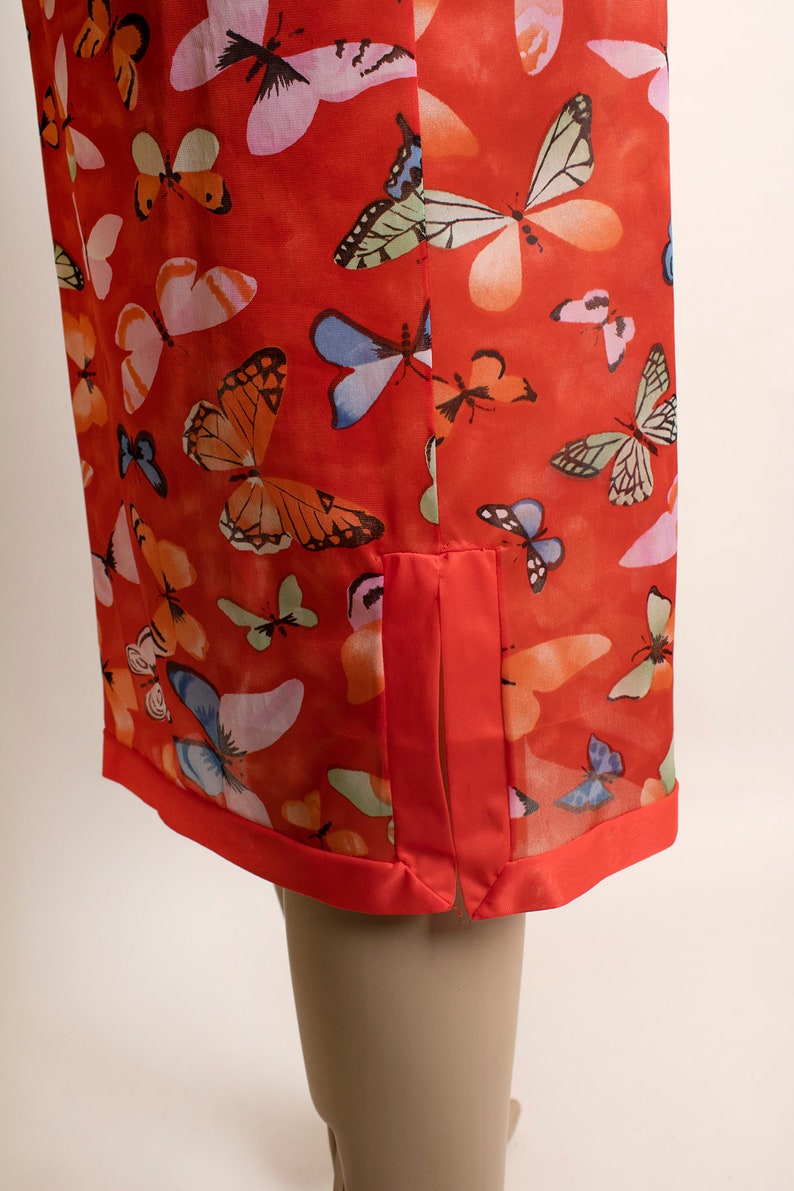 May include: A red sheer dress with a butterfly print. The dress has a side slit and a red satin trim.