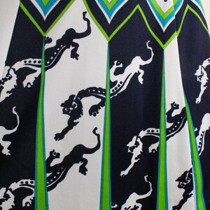 May include: White fabric with a black and green geometric pattern. The pattern features stylized black animal figures on a white background. The fabric has a polka dot pattern in black on white.