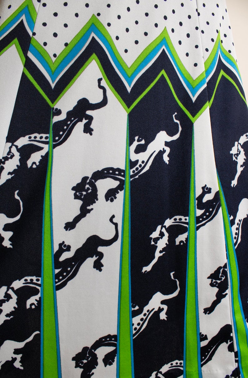 May include: White fabric with a black and green geometric pattern. The pattern features stylized black animal figures on a white background. The fabric has a polka dot pattern in black on white.
