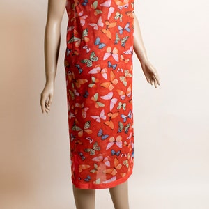 May include: A red dress with a mandarin collar and short sleeves. The dress is covered in a pattern of colorful butterflies.