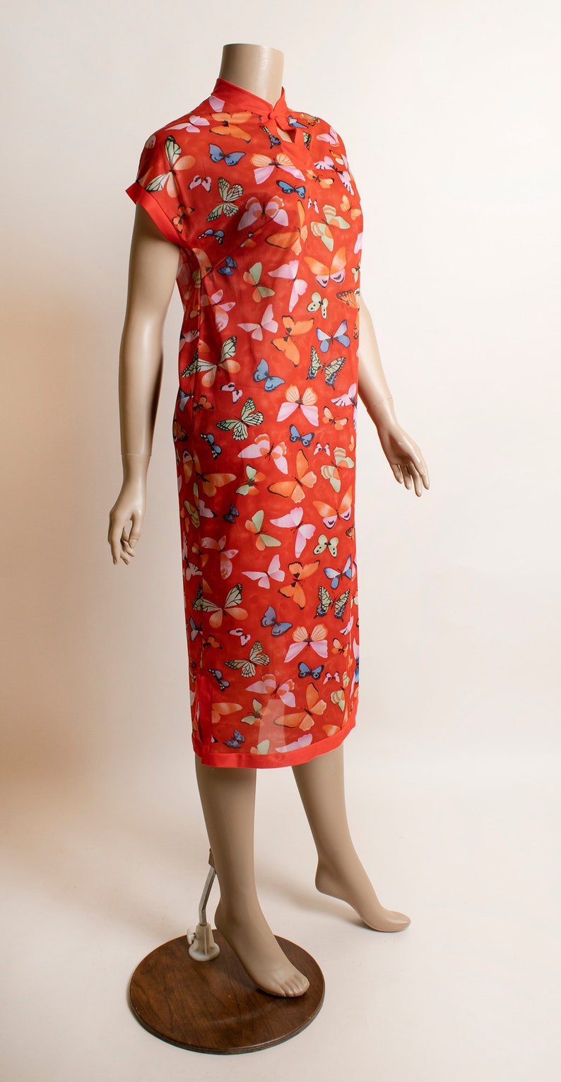 May include: A red dress with a mandarin collar and short sleeves. The dress is covered in a pattern of colorful butterflies.