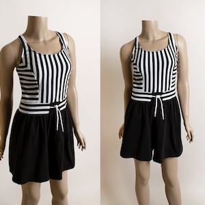 May include: Black and white striped swimsuit with a black skirt. The swimsuit has a scoop neck and thin straps. The skirt has a drawstring waist.