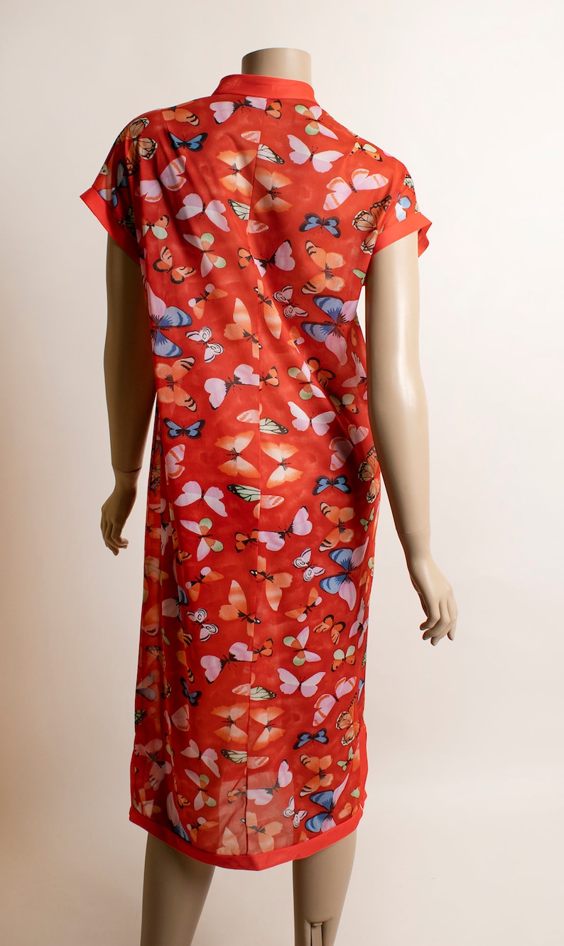 May include: A red, short-sleeved dress with a mandarin collar and a butterfly print. The dress is made of a sheer fabric and has a loose fit.