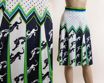 May include: A white, black, and green A-line skirt with a geometric pattern of black panthers and white polka dots. The skirt has a green and blue waistband.