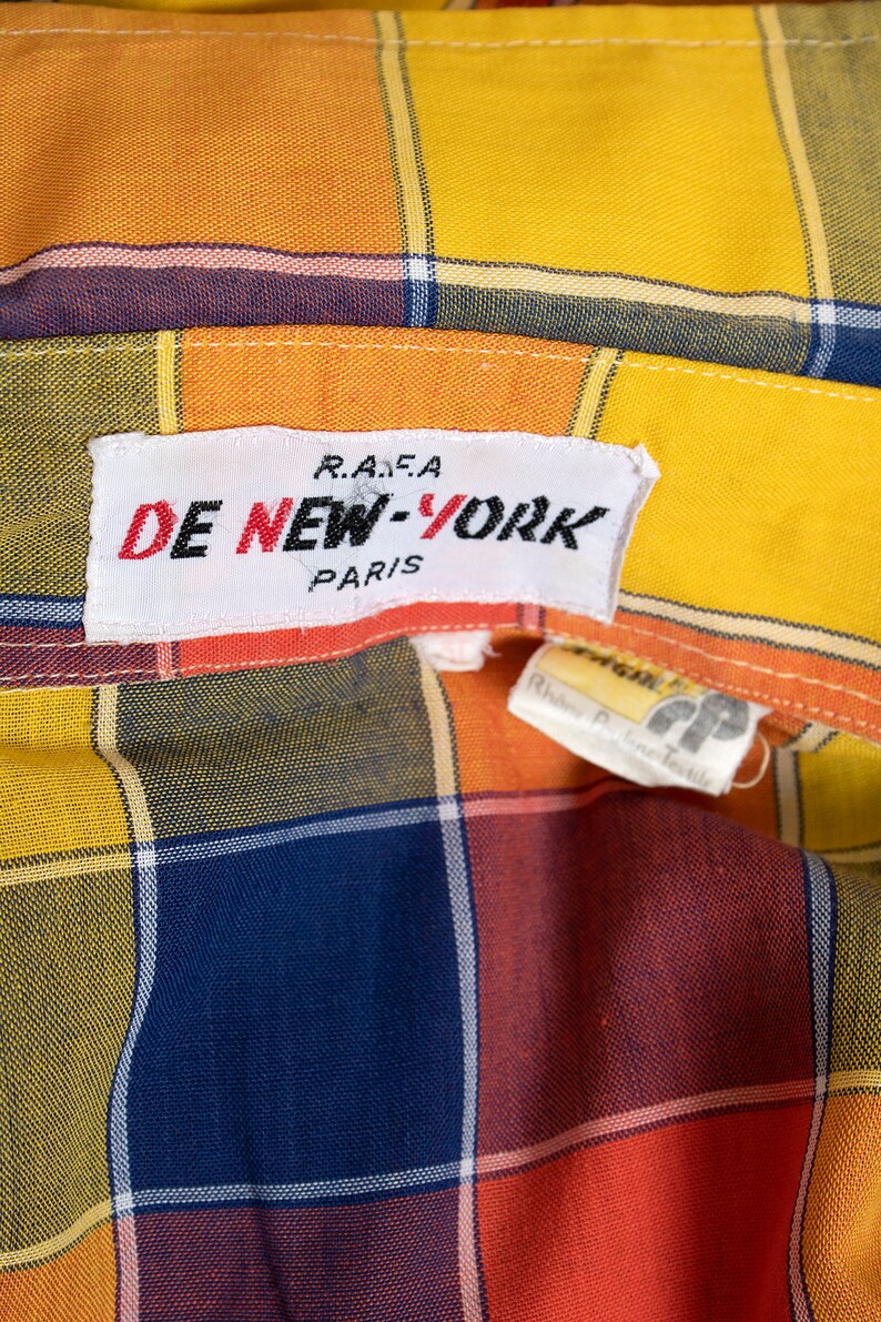 May include: A yellow, orange, red, and blue plaid shirt with a white label that reads "DE NEW-YORK R.A.F.A. PARIS".