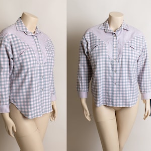 May include: A long-sleeved, button-down shirt with a plaid pattern in shades of pink and blue. The shirt has a pointed collar and two chest pockets.