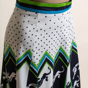 May include: A white skirt with a black polka dot pattern and a green, blue, and black geometric print. The skirt has a wide waistband with a green, blue, and black striped pattern.