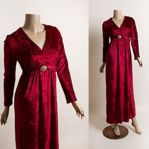 May include: A long, red velvet dress with a V-neckline and a small gold button at the waist.
