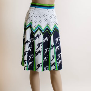 May include: A white skirt with a black and green geometric pattern featuring a repeating design of leaping panthers. The skirt has a white polka dot pattern at the top and a green, blue, and black waistband.