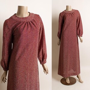 May include: A long-sleeved, red, sparkly dress with a high neckline and a gathered detail at the neckline. The dress has long, gathered sleeves and a flowing skirt.