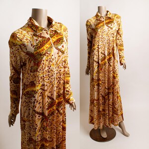 May include: A floor-length long-sleeve dress in a light cream color featuring a repeating pattern of orange and brown leopards amidst stylized tree branches. The garment includes a collared neckline and a full-length front zipper closure.