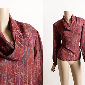 May include: A red, blue, and gold paisley print blouse with a cowl neck and long sleeves.