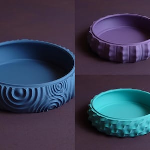 Può includere: Quattro ciotole decorative con diversi motivi testurizzati. Le ciotole sono in tonalità di blu, viola e verde.