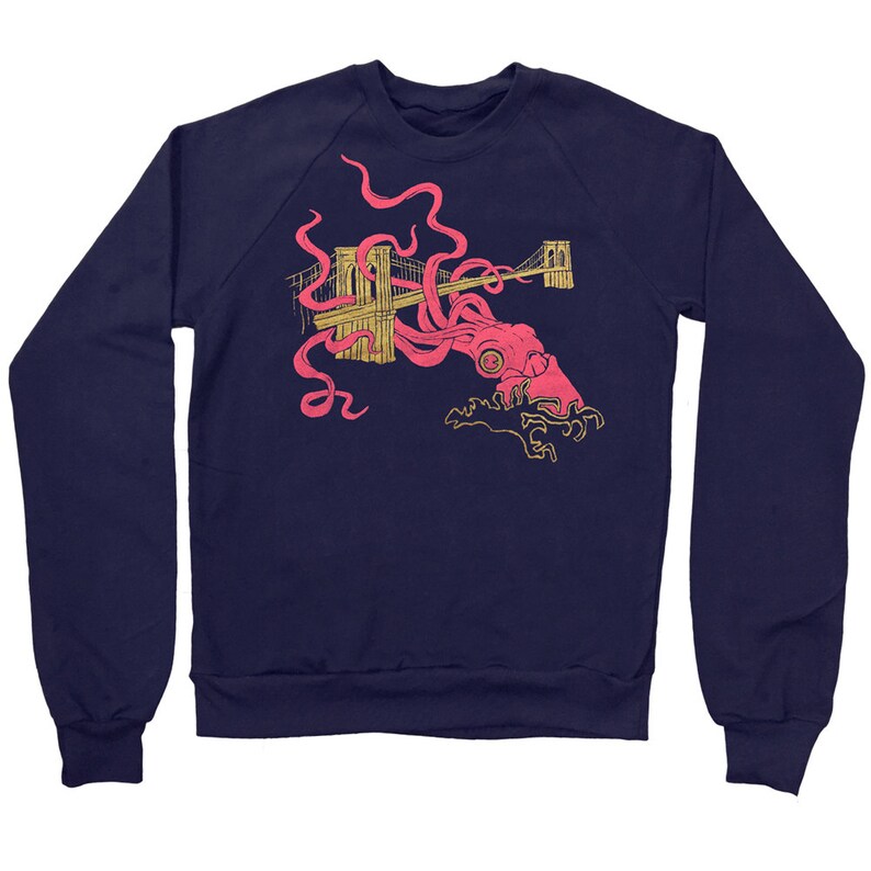 May include: A navy blue sweatshirt with a graphic print of a pink octopus attacking the Brooklyn Bridge. The bridge is outlined in gold.