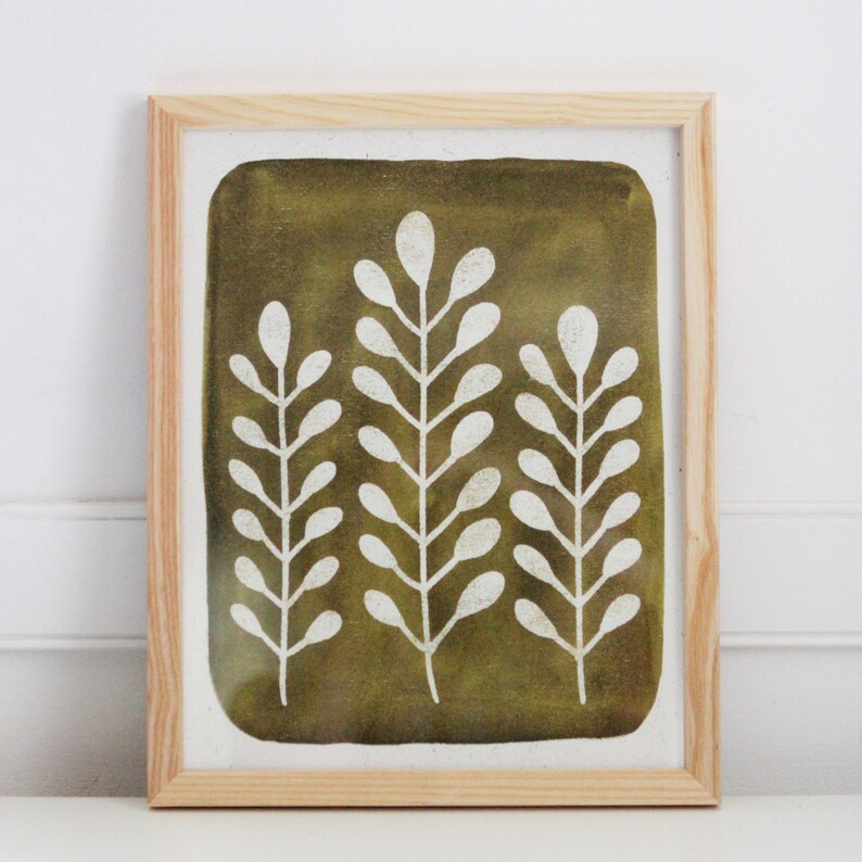 May include: A framed print with a green background and white stylized floral design. The print features three branches with leaves.