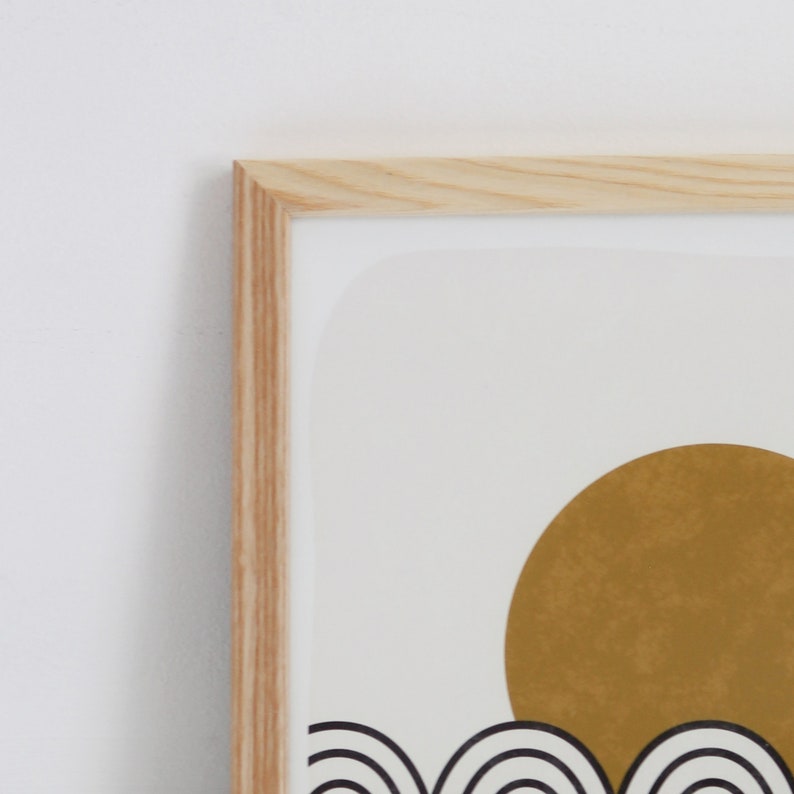 May include: A framed print with a minimalist design featuring a large gold sun over a series of black and white waves.