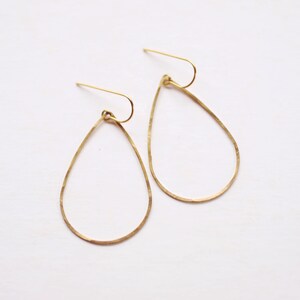 May include: A pair of gold teardrop-shaped earrings with a hammered finish.