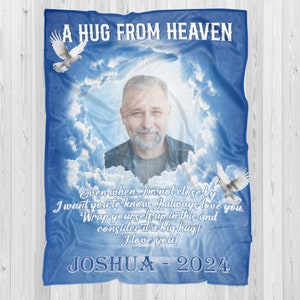 May include: A blue and white memorial blanket with a photo of a man and the text "A Hug From Heaven". The text also reads "Even when I'm not close by I want you to know I always love you. Wrap yourself up in this and consider it a big hug! I love you! Joshua - 2024".