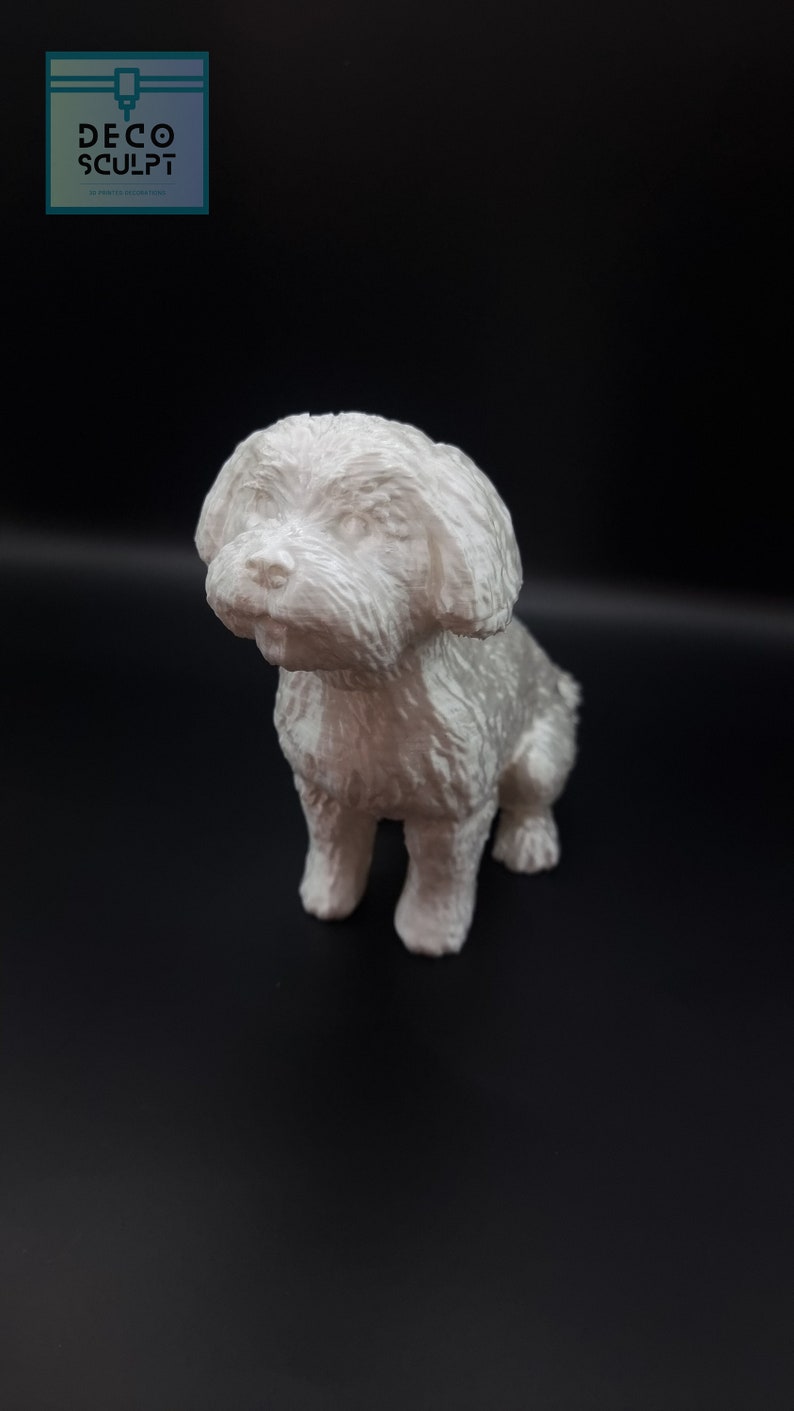 May include: A white 3D printed figurine of a small dog sitting with its head tilted to the side. The dog has a fluffy coat and a sweet expression.