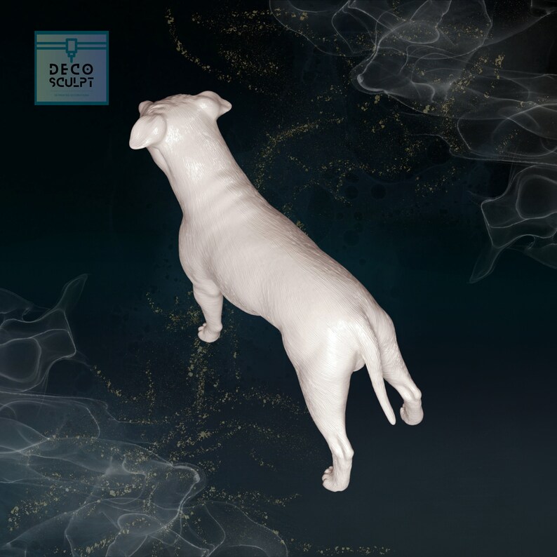 May include: White ceramic sculpture of a dog viewed from above. The dog is standing with its tail curled up. The sculpture is on a dark blue background with a white, swirling pattern.