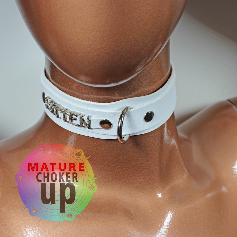 May include: White leather choker with silver metal accents and the word "Kitten" spelled out on the front.
