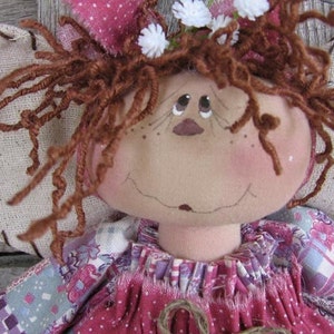 May include: A handmade rag doll with brown yarn hair, a pink and white floral print dress, and a white flower crown.