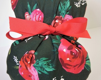Puede incluir: Un gorro de quirófano verde oscuro con un lazo rojo y un estampado floral de rosas rosas y rojas.