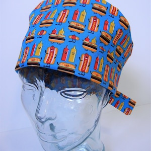 May include: A blue scrub hat with a pattern of cartoon hot dogs, hamburgers, and ketchup and mustard bottles.