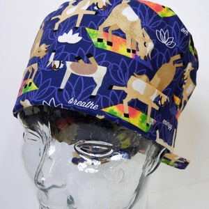 May include: A blue and white patterned surgical scrub hat with a design of goats doing yoga. The hat has the words "breathe" and "energy" printed on it.